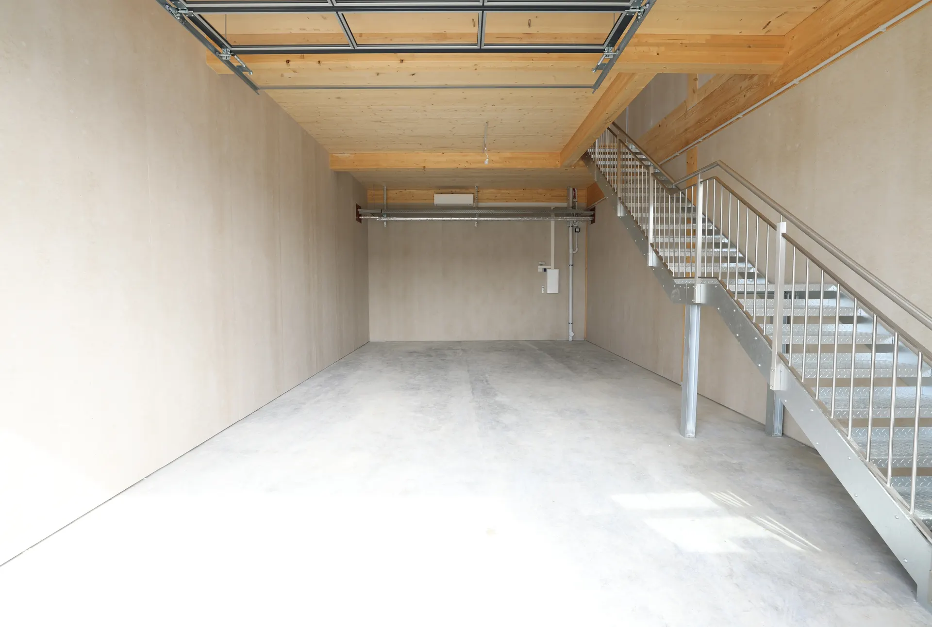 Erdgeschoss mit Betonboden, Treppe zum Obergeschoss und Sektionaltor